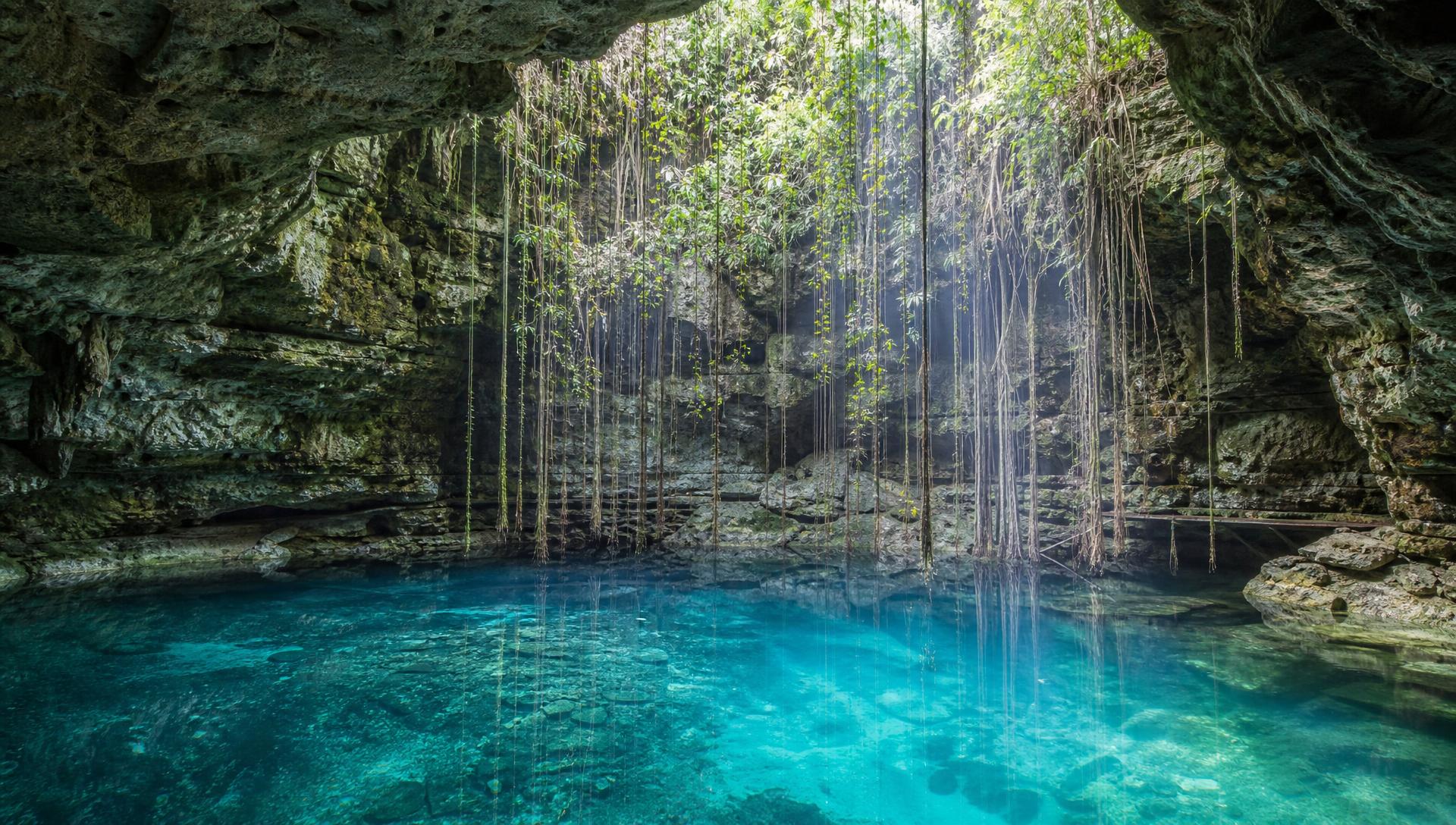 Turquoise water inside a Tulum cenote lit by a shaft of daylight