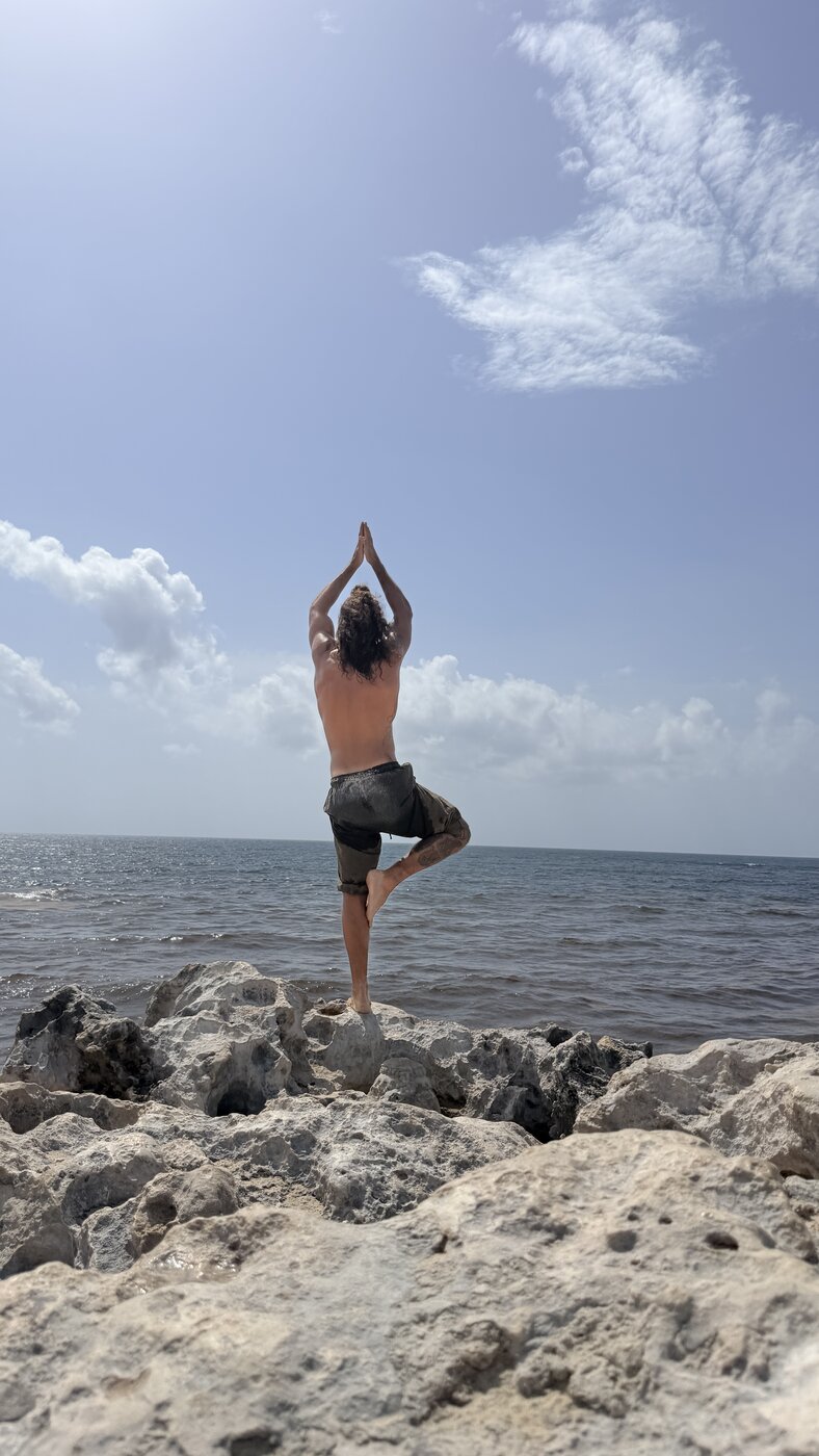 Stephen walking a Tulum beach path carrying a yoga mat