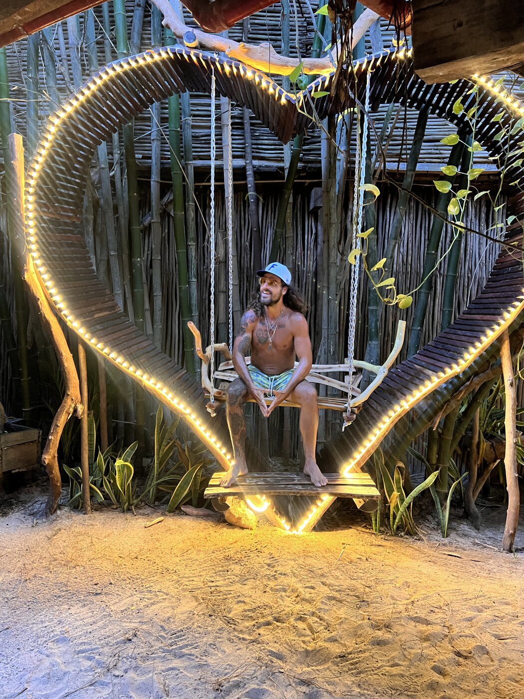 Illuminated heart-shaped swing in a Tulum jungle garden at night